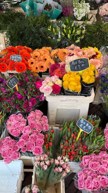 A vibrant display of freshly arranged flower bouquets and potted plants at a florist shop, showcasing a variety of colorful flowers including bright pink roses, orange gerbera daisies, yellow roses, p